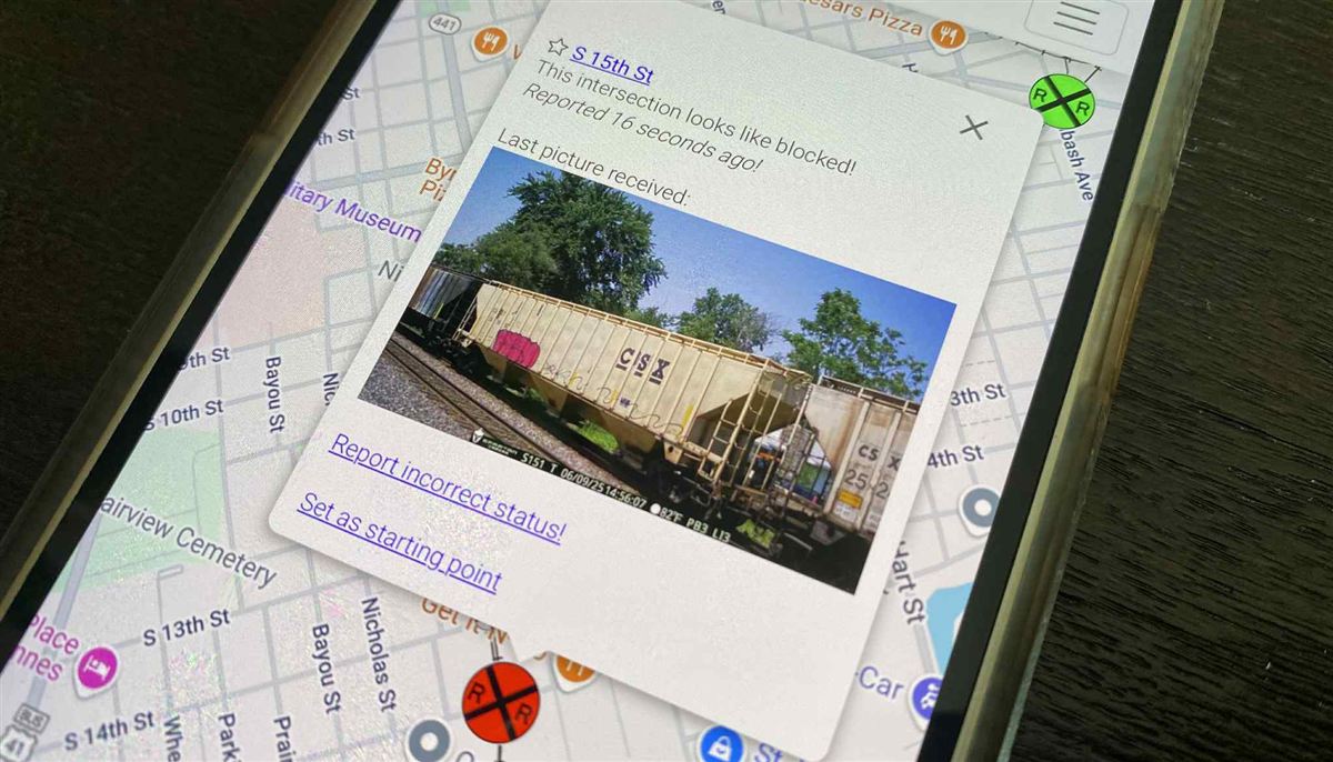 The InterFact app on a phone, showing a railroad crossing reported as blocked with the latest camera picture of a train.